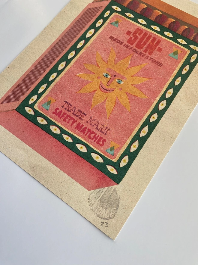 This is a vintage matchbox illustration created in Caridade's distinctive style, bright colours, patterns, distressed textures that give the image a retro feel and happy and friendly elements. The image depicts a sun smiling and it reads Sun, Made in Folkestone with Safety matches as the sub-text.