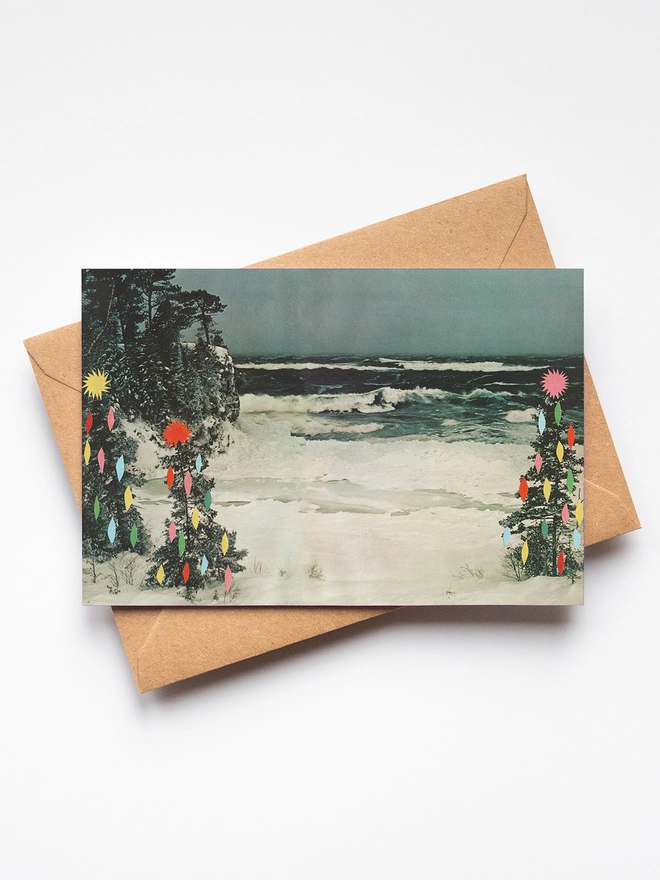 A vintage beach scene covered in snow with surrounding trees decorated with colourful fairy lights.