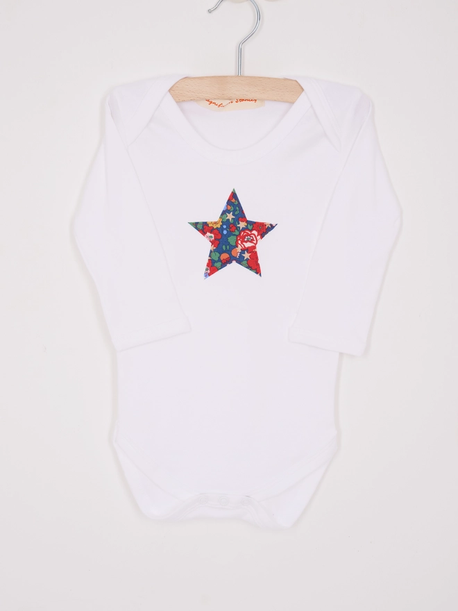 a christmas liberty print floral print star white bodysuit, close up on the appliqué stitching 