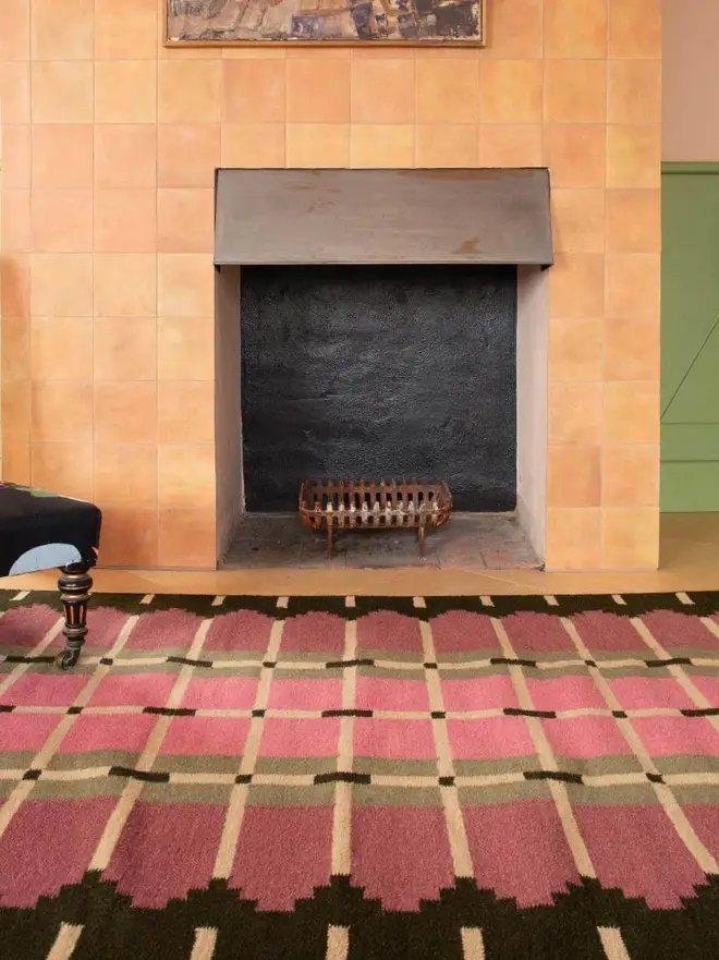 Corbie Flatweave Rug, a colourful rug sitting in a decorated room. It is accompanied by other household items. 