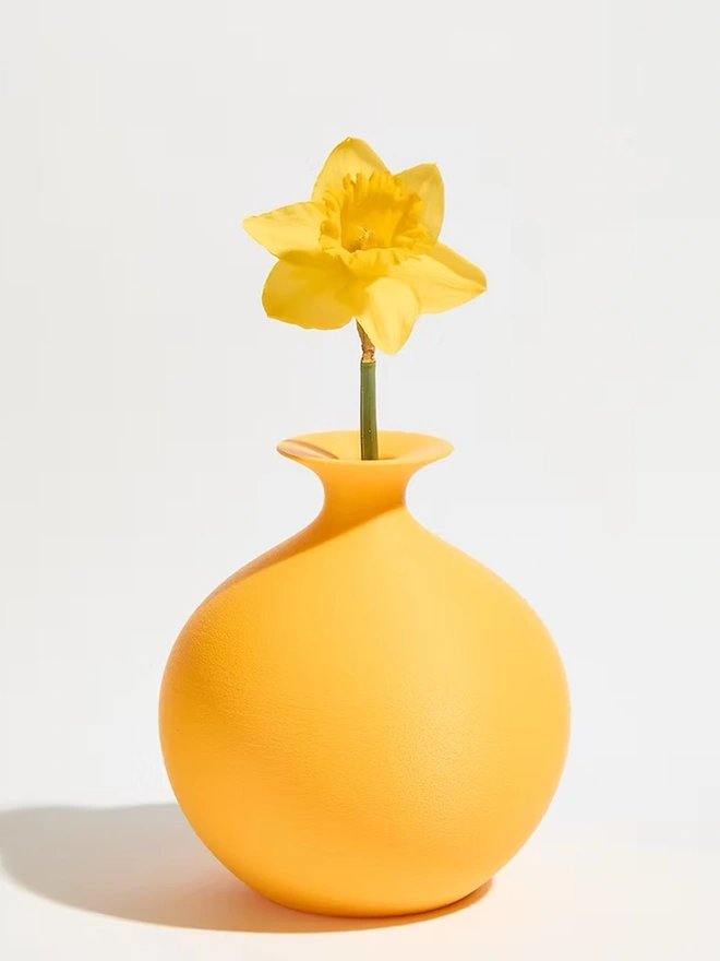 round shaped yellow 3d printed vase with yellow flower