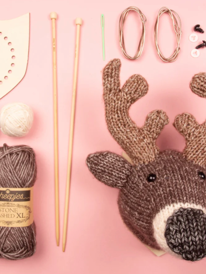 Mini Deer Head Knit Kit. A deer head with knitting needles, yarn, and equipment.