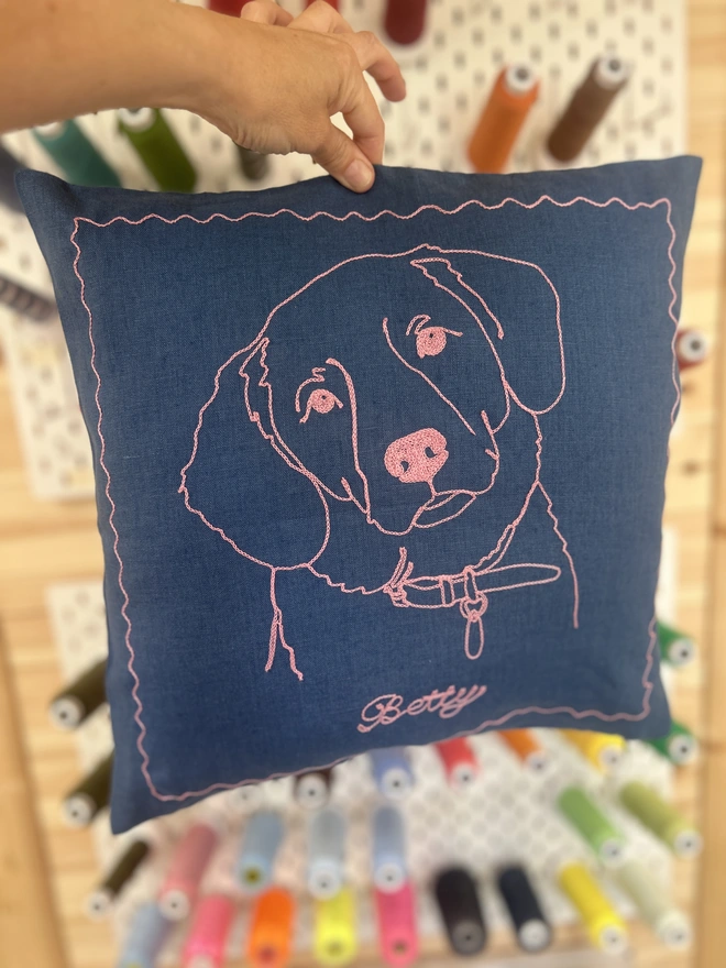 blue linen pillow with embroidered dog in pink thread