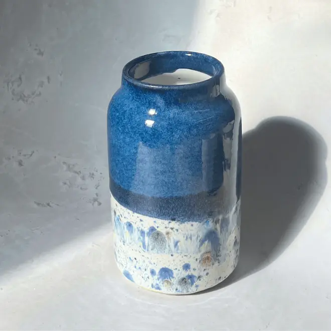 Shoreline Large Vase, a colourful vase placed on a stone surface in front of a plain backdrop. 