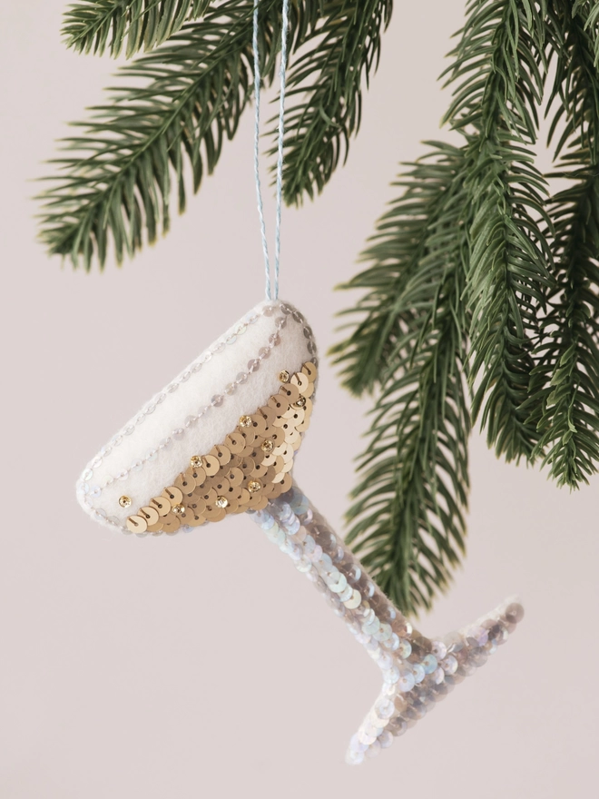 A golden sequinned champagne coupe glass on a tree