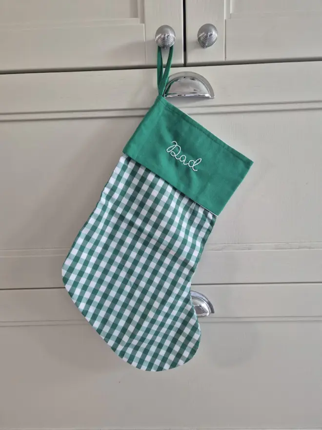 beige gingham stocking with personalised embroidered name hanging