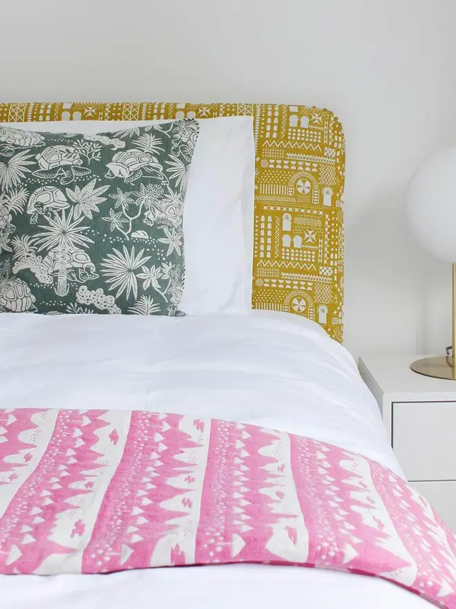 Pink Belle Mare Woven Throw, a bed decorated with a pink throw on top of its white duvet. 