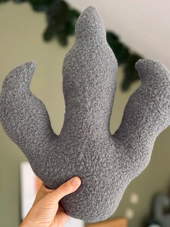 boucle dinosaur footprint cushion. a grey dinosaur foot cushion.