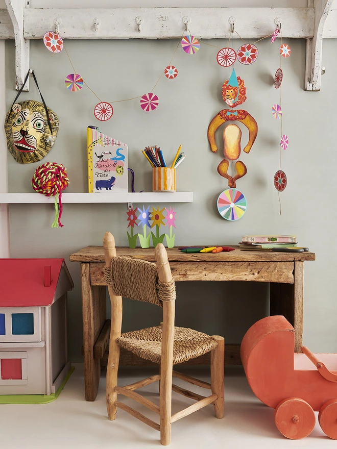 An image of the tiger mobile hanging over a cute kids desk next to a dolls house and orange wooden pram