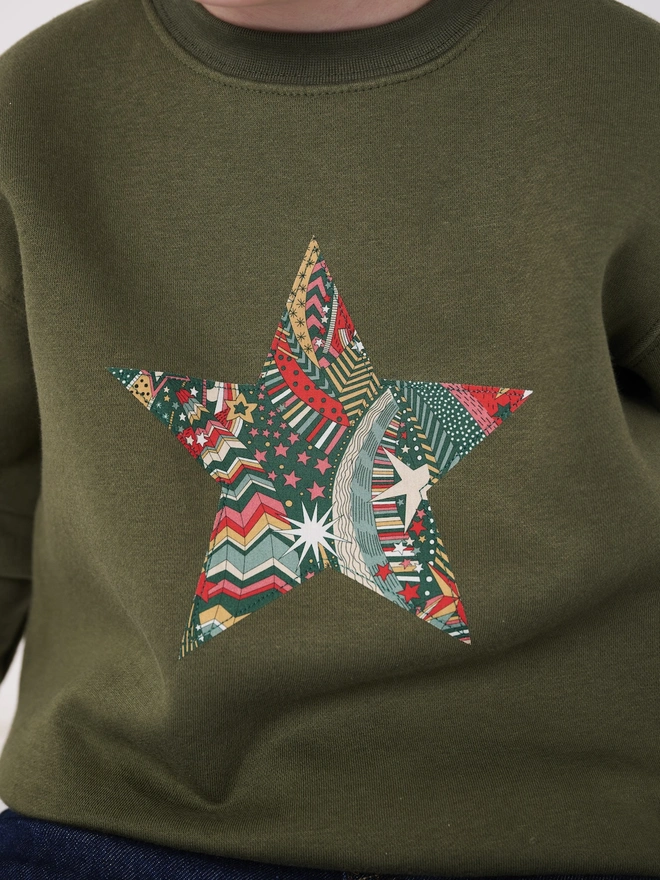 a 5 year old boy wearing a khaki christmas sweatshirt with a festive liberty print star on the front