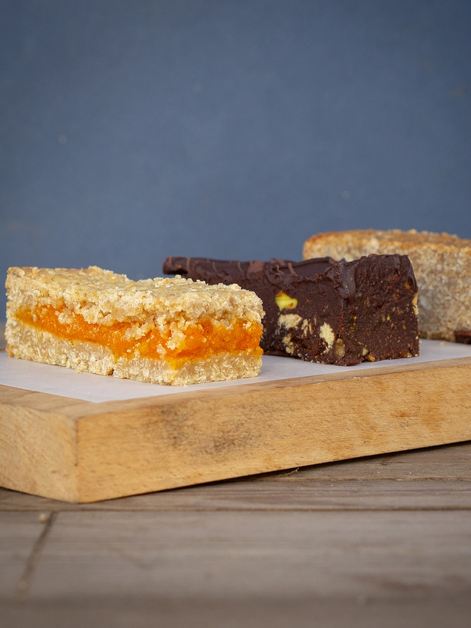Fig and Pistachio Tiffin is a rich dark chocolate sauce mixed with buttery digestive biscuits, bright green pistachios and chewy figs. Topped with a layer of the finest dark Belgian chocolate and drizzled with crisp milk chocolate to finish. 