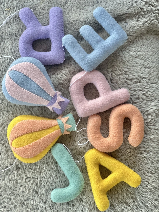 Personalised Name Icon Garland, a child’s name banner hanging from a white shelf, nursery decoration, baby gift 