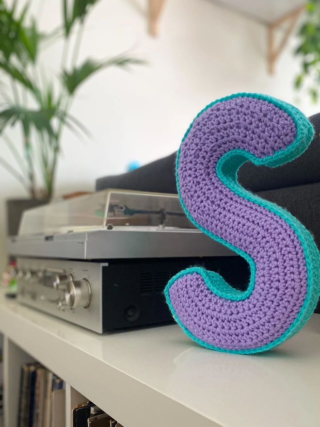 Crochet Cushion shaped like an S on a shelf