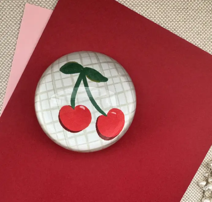 Decoupage cherry Paperweight. Paperweight on a sheet of red paper on a wooden table. 