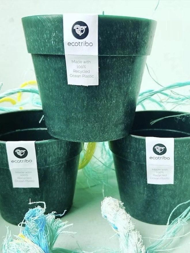 Small Green Ocean Plastic Plant Pot , a group of green recycled plant pots against a colourful backdrop. 