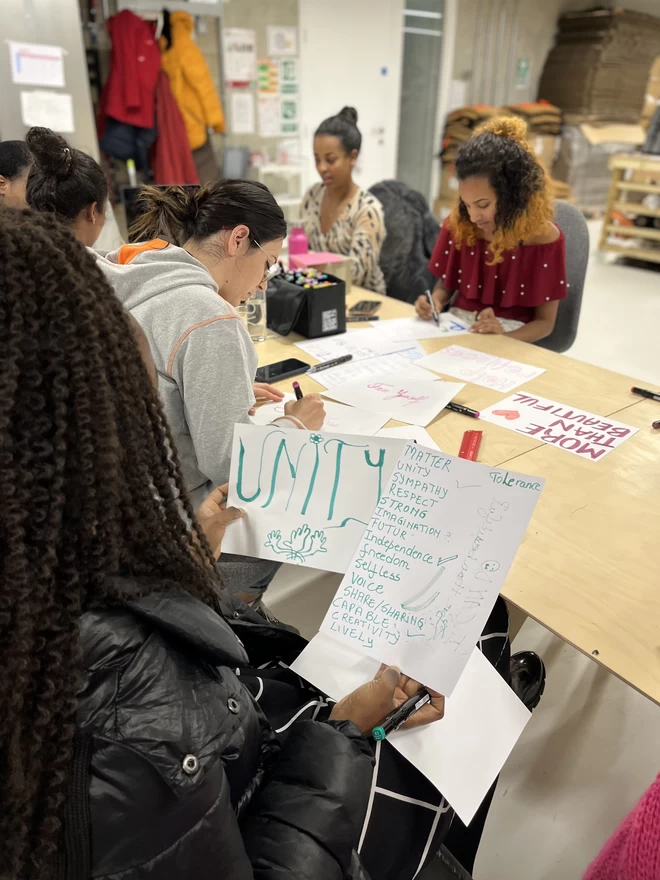 A team of women from a refugee background, choosing the words for the front of the cushion.