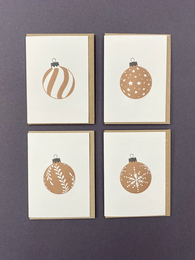 Four metallic gold Christmas baubles on small cards with envelopes