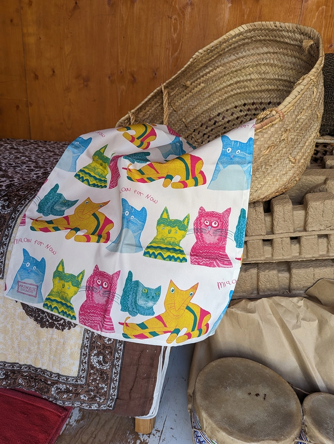 Close up of miaow for now 100% organic cotton charity tea towel in blue pink & yellow