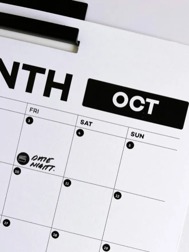 Close-up of wall planner showing October month with date night icon sticker