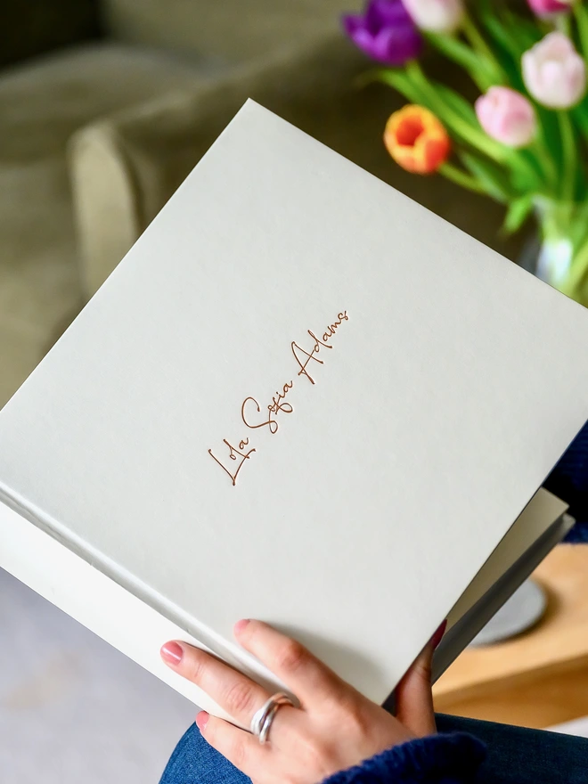 A close up image of an ivory photo album which has been printed on the front with a calligraphy handwriting 