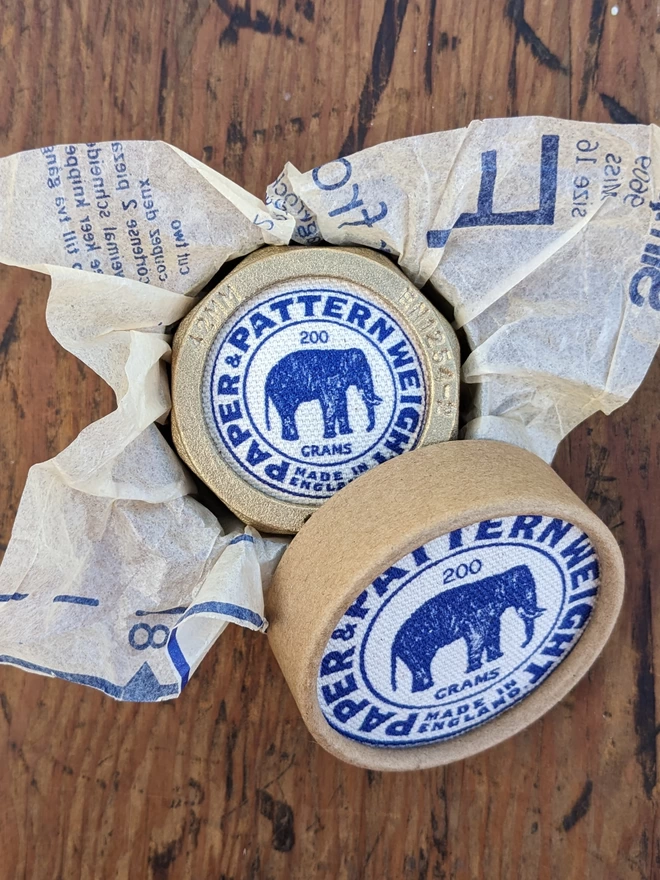 Blue elephant brass pattern & paper weight in box with lid open and wrapped in vintage sewing pattern tissue