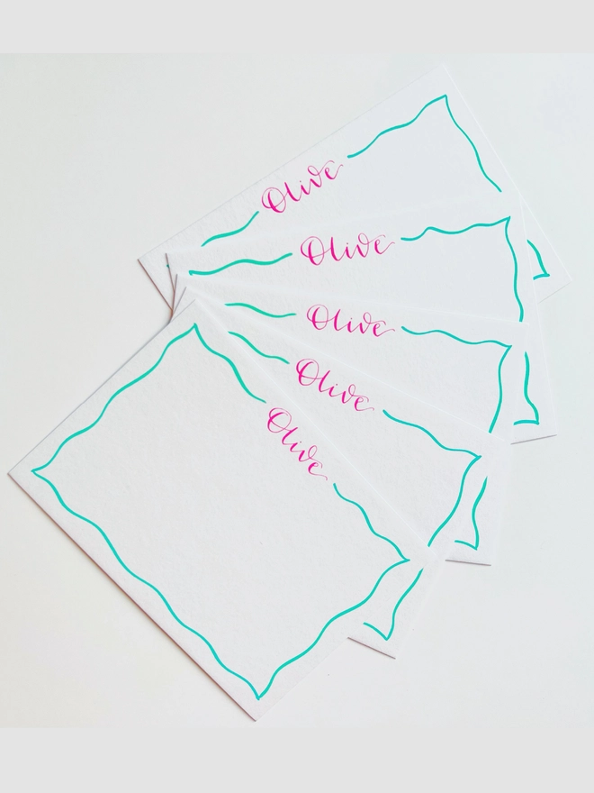 Five white notecards with Olive written in bright pink calligraphy and a wavy mint coloured border around the edge of the card.