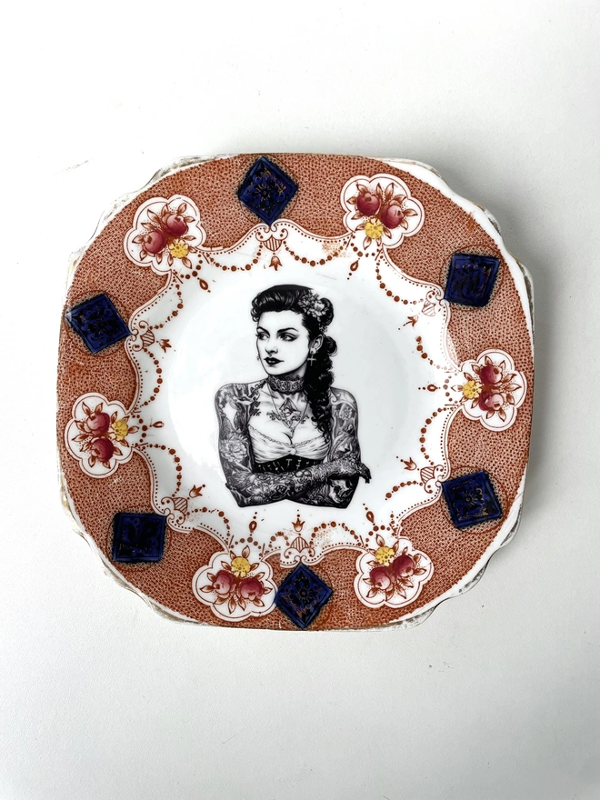 a vintage plate with ornate border, within the centre i have printed the vintage style image of a victorian tattooed sailor woman