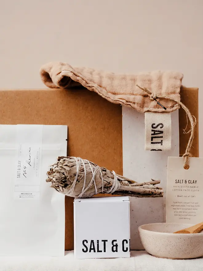 Natural products gift set including a face cloth, sage smudge, fizzing bath bomb, face mask and a bowl with spoon.