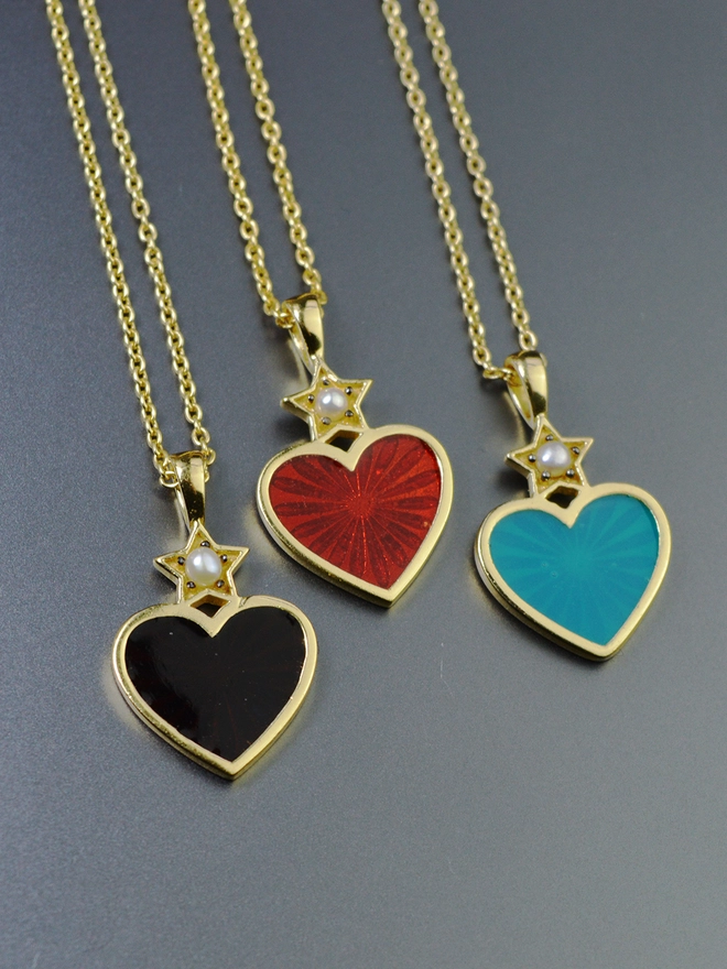 Three Heart necklaces in black, red and turquoise enamel, all with a pearl star detail