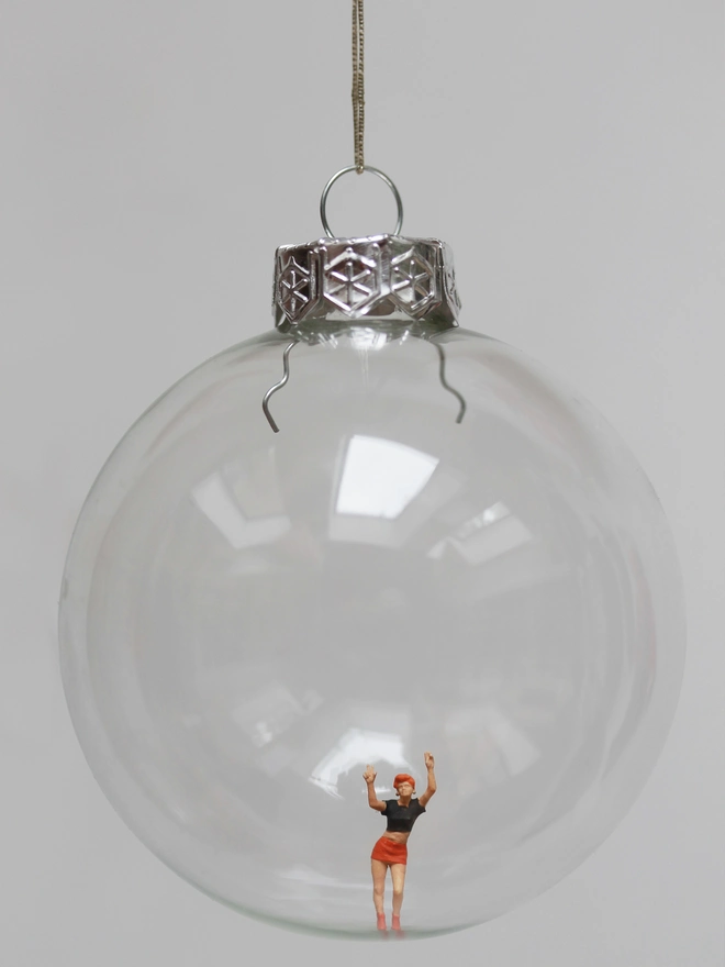 Miniature figure of a dancing festival goer, in a glass Christmas bauble 
