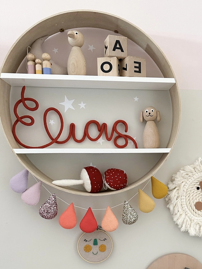 Personalised custom name sign decorating a shelf in a child's bedroom.