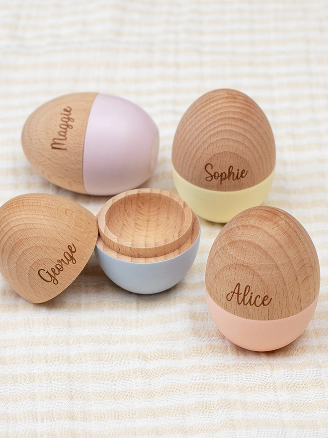 Hollow wooden eggs in pastel shades engraved with names