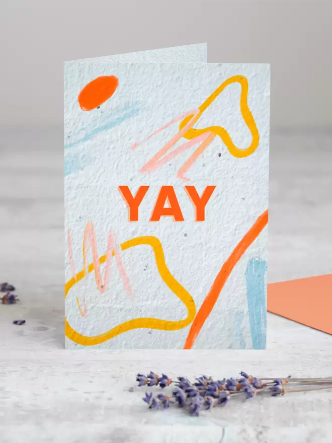 Plantable Card with ‘YAY’ in the centre of the card with an abstract pattern around it with a sprig of Lavender placed in the foreground