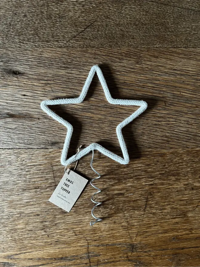 A medium sized string wrapped wire star with coil and label on an oak table