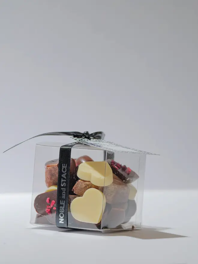 Chocolates heart cubes wrapped in a clear plastic box with a black ribbon. 