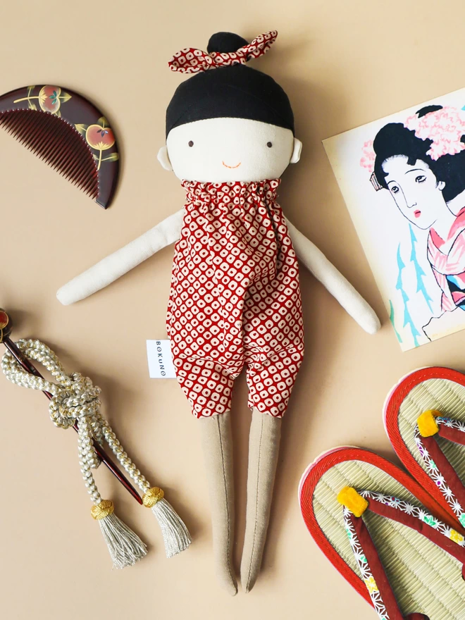 Fabric textile doll with black hair light skin and outfit with red spots