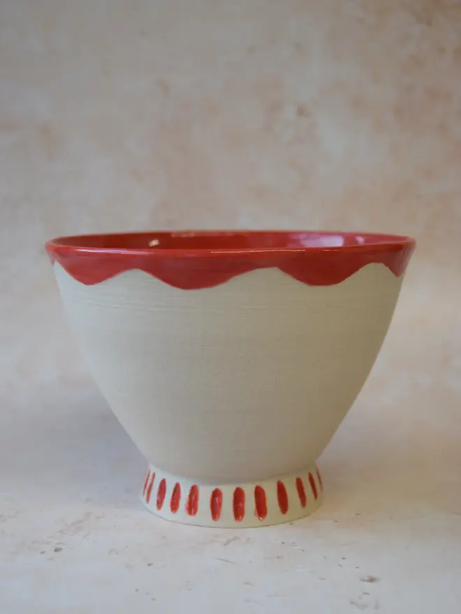 Handmade ceramic bowl — side view with red scalloped rim and dotted base