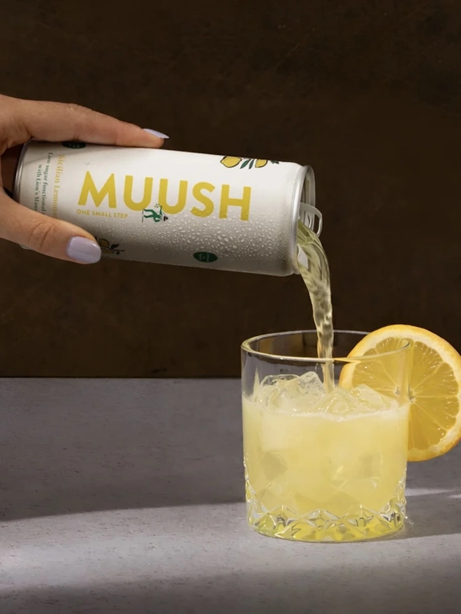 Sicilian Lemonade Cans (Pack Of 12), a soft drink being poured from a can on a stone surface. 
