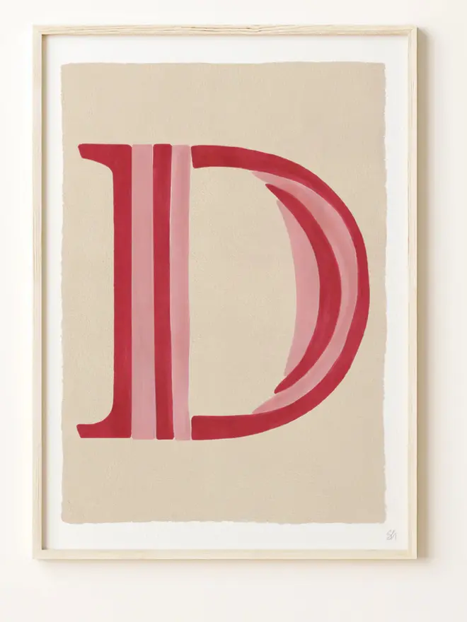 Framed wall art print featuring a large decorative letter “D” in humbug stripes
centered on a white background. 