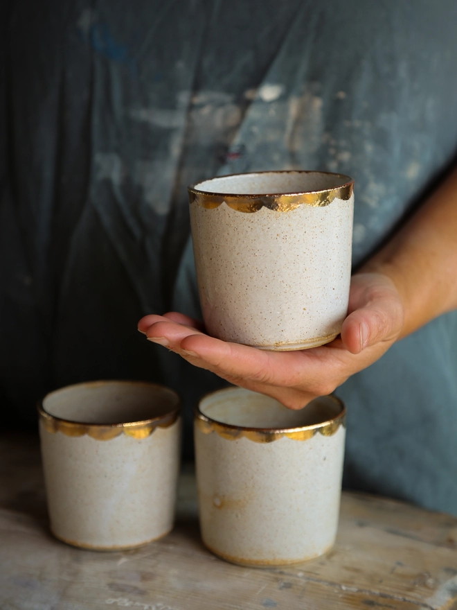 white stoneware drinking beaker with gold scallop decoration around the rim