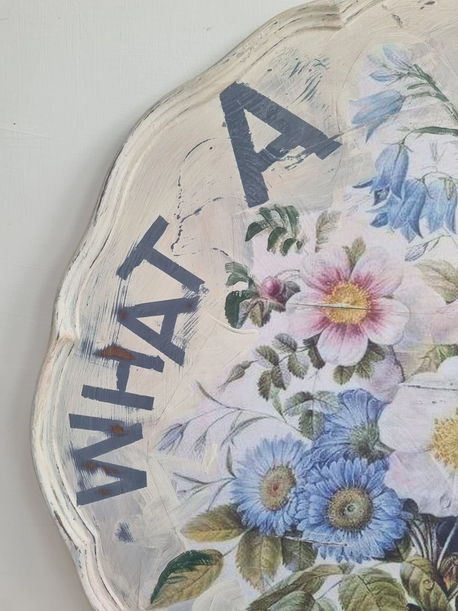 Art Panel made from a 'pie crust' table top. A pale background with mauve flowers and writing in mauve that says 'what a beautiful day'.