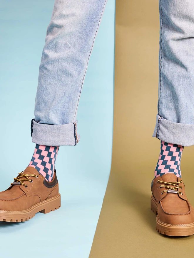 man wearing pink and teal checked socks, jeans and brown shoes