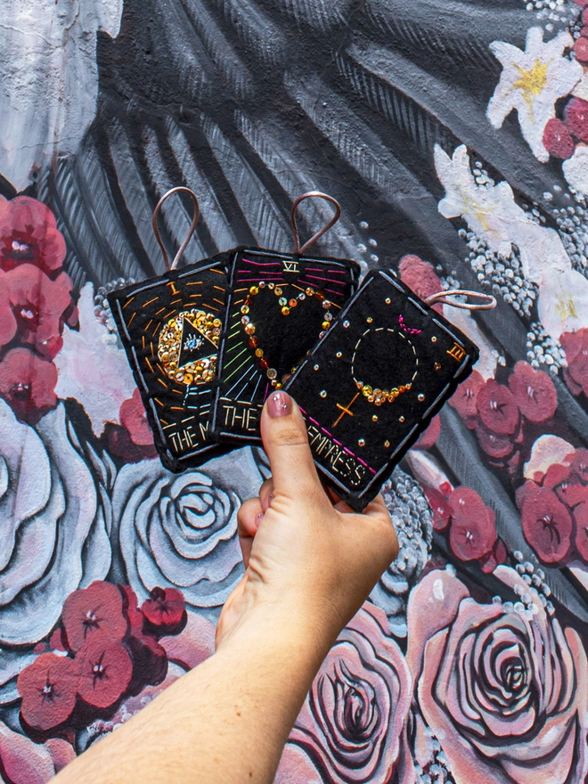 A handcrafted felt ornament with sequins and embroidery depicting "The Lovers" tarot card. Colourful embroidery with a heart shape. Also accompanied by “The Empress and The Magician”