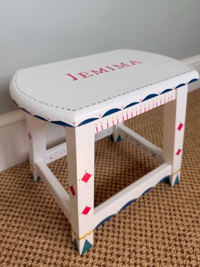 Jemima Personalised Hand Painted Stool. A white stool with intricate red and blue designs and personalisation.