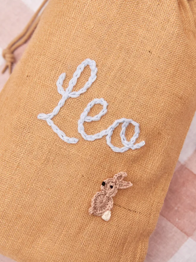 jute drawstring sack with brown knitted bunny decoration and blue 'Leo' name nexton red gingham table cloth