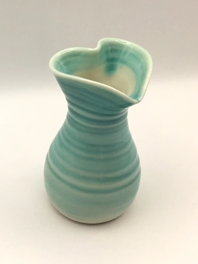 porcelain turquoise heart shaped vase. a turquoise vase with a heart shape opening and round base.