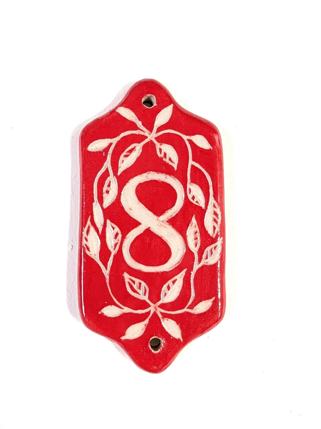 Red Sgraffito Leaf Address Tile. A tile with ‘8’.