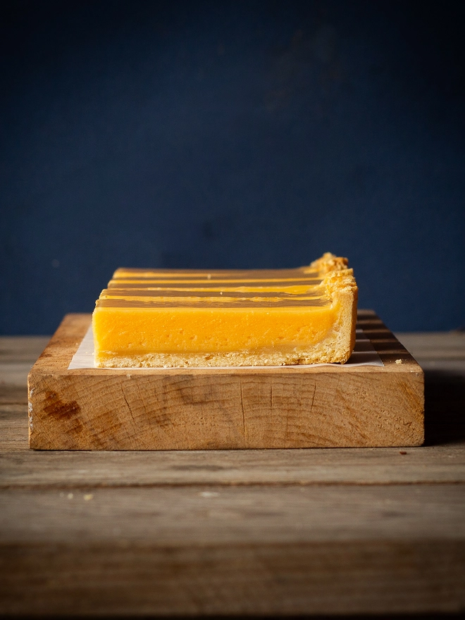 Side profile of Lemon Tart showing a buttery pastry base and a warm yellow filling