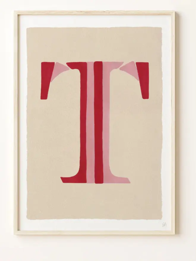Framed wall art print featuring a large decorative letter “T” in humbug stripes
centered on a white background. 