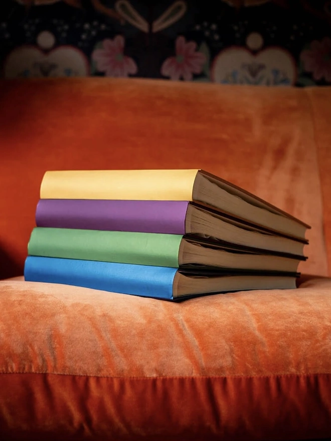 Beautiful 'Jewel' Hardback Photo Albums with plain covers, stacked on an orange sofa. 